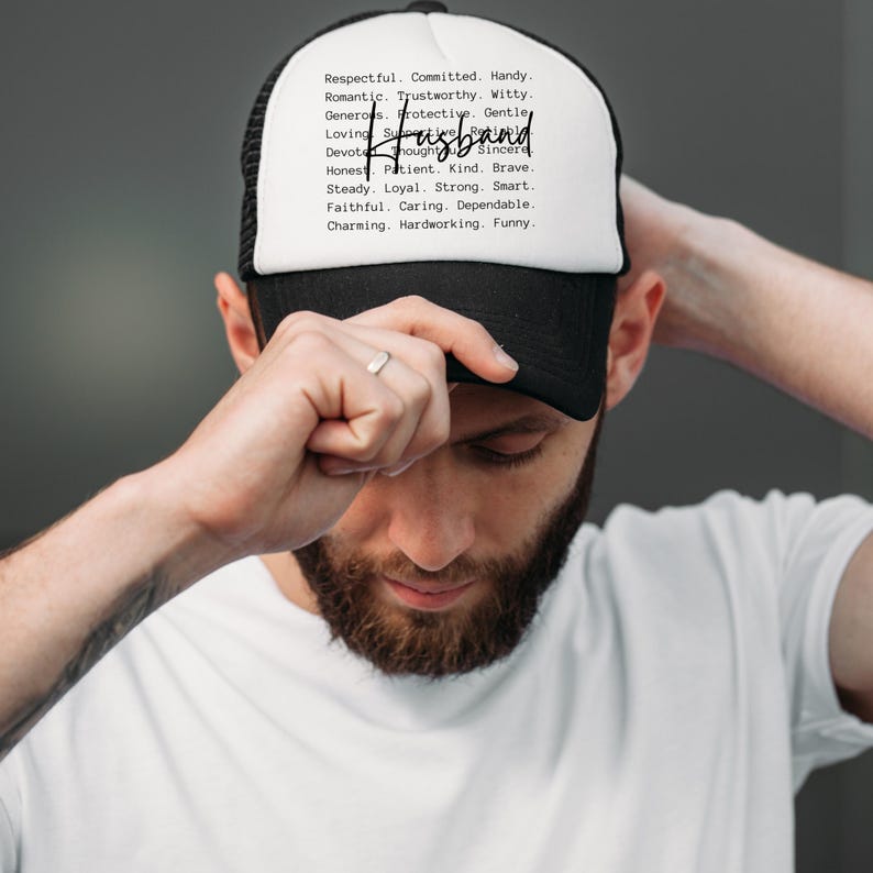 May include: A black and white trucker hat with the word "Husband" in a handwritten font. The hat's white front panel lists positive attributes like "Respectful," "Kind," and "Funny."