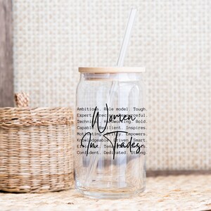 May include: A clear glass jar with a bamboo lid and a straw. The jar has a black and white graphic with the text "Women in Trades" and a list of positive attributes.