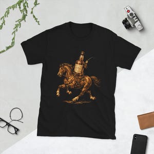 Puede incluir: Camiseta negra con una ilustración en tonos sepia de una botella montando a caballo. La botella se representa como un jinete, sosteniendo un látigo. El caballo está al galope. El diseño está centrado en la camiseta.