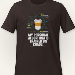 May include: A dark brown short-sleeve t-shirt featuring a graphic of a coffee cup with a tired face. The design includes technical data boxes labeled 87% Exhausted, 88% Overthinking, and 100% Caffeinated, with the text MY PERSONAL ALGORITHM IS TRAINED ON CHAOS.