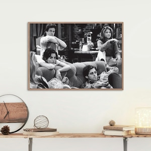 Puede incluir: Foto en blanco y negro de cuatro amigos sentados en un sofá. Los amigos sonríen y miran a la cámara. La foto está enmarcada en un marco de madera.