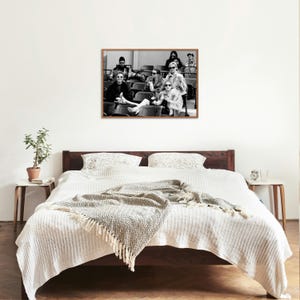 May include: Black and white photograph of a group of people sitting in stadium seats. The people are wearing sunglasses and are looking at the camera. The photograph is framed in a wooden frame.
