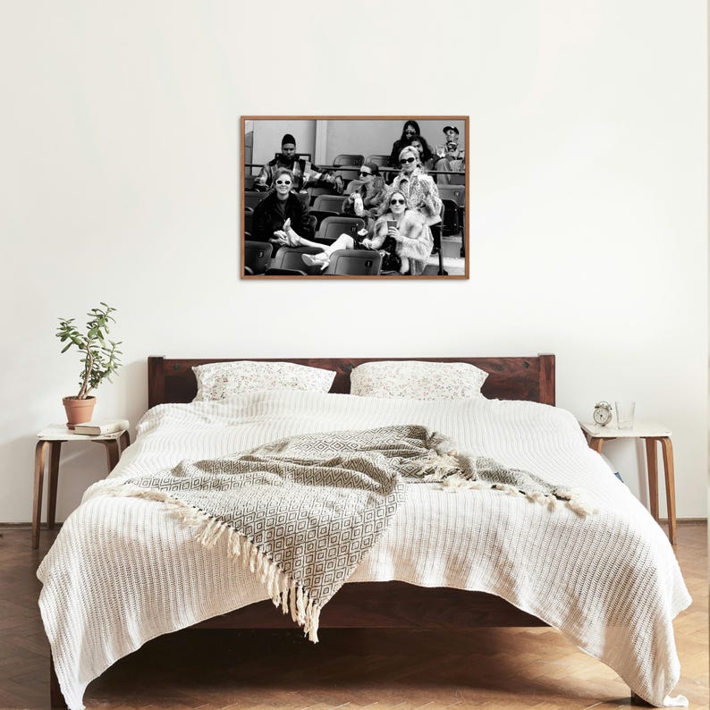 May include: Black and white photograph of a group of people sitting in stadium seats. The people are wearing sunglasses and are looking at the camera. The photograph is framed in a wooden frame.