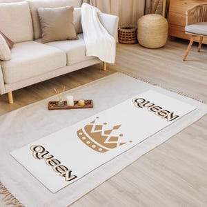 May include: White yoga mat with a brown crown and the word "Queen" printed in a stylized font on each end.