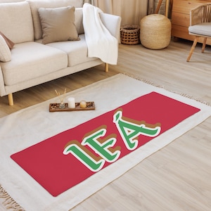 May include: A red and green personalized doormat with the name "LEA" in a stylized font.