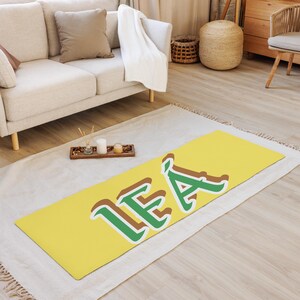 May include: A yellow yoga mat with the name "LEA" written in green and brown letters.