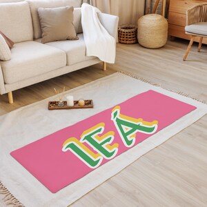May include: A pink yoga mat with the name "LEA" written in green and yellow letters.