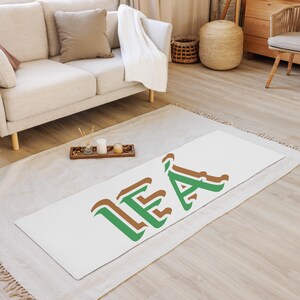 May include: White yoga mat with the name "LEA" written in green and brown letters.