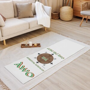 May include: White yoga mat with a green and brown logo that says "ALWO" and "Egre Ire Alwo" with a brown circle in the center that says "Idea" and has arrows pointing to it. The text "Spiritual Services" is written below the circle.