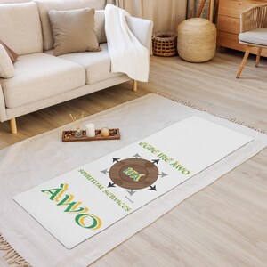 May include: White yoga mat with a green and yellow logo that says "Awo" and a brown circle with the word "Idea" inside. The circle is surrounded by arrows pointing in different directions. The text "Spiritual Services" is written below the circle and the text "Egie Ire Awo" is written above the circle.