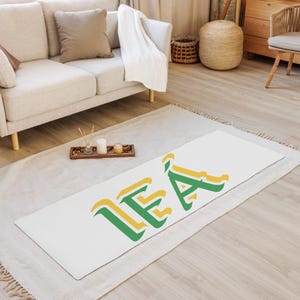 May include: White yoga mat with the word "LEA" printed in green and yellow letters.
