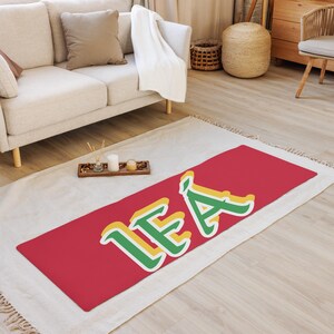 May include: Red, green, and yellow doormat with the word "LEA" in a stylized font.