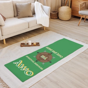 May include: Green yoga mat with a brown circle in the center that says "TEA" and arrows pointing in different directions. The words "EGNE TRÉ AWÓ" and "ALWÓ" are written in yellow on the mat. The words "SPIRITUAL SERVICES" are written in yellow on the mat.