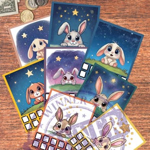 May include: A collection of colorful cards featuring adorable cartoon bunnies against starry night backgrounds. Some cards have a "WINNER" stamp. The cards are arranged on a wooden surface with money and coins.