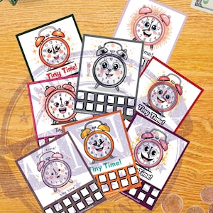 May include: A collection of colorful cards featuring cartoon alarm clocks with smiling faces. Each card has the text "Tiny Time!" and a grid for tracking savings. The clocks are in various colors, including red, pink, and orange.