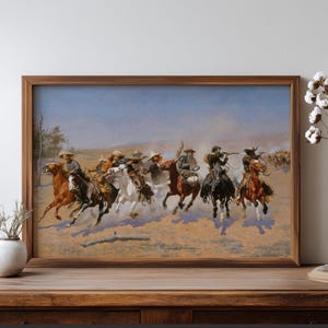 May include: A framed painting shows a Western scene with cowboys on horseback, pursuing cattle across a dusty plain. The artwork features a dynamic composition with riders in hats and chaps, set against a blue sky and tan landscape.
