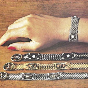 May include: A collection of macrame bracelets in various colors and patterns. One bracelet is worn on a wrist, while three others are displayed below. The bracelets feature intricate knotting and decorative buckles, showcasing a handcrafted aesthetic.