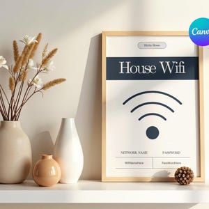 Op de afbeelding: Een ingelijste print met de tekst "House Wifi" en een wifi-symbool. De print zit in een licht houten frame en staat op een witte plank met vazen en decoratieve bloemen. Er ligt ook een kleine dennenappel op de plank.