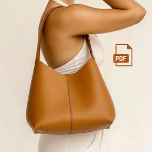 May include: A tan leather shoulder bag with a curved shape and a vertical seam down the center. The bag has a long strap and is shown against a white background. A PDF icon is visible.