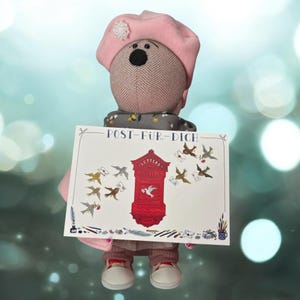 Könnte beinhalten: Ein Stoffbär mit rosa Baskenmütze, der ein Schild mit der Aufschrift "POST-FÜR-DICH" hält. Das Schild zeigt einen roten Briefkasten und Vögel, die Briefe tragen. Der Bär trägt einen grauen Schal und eine rosa Hose.
