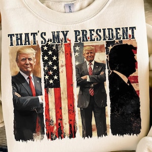 May include: A cream-coloured sweatshirt with a graphic print of two men in front of an American flag. The text "THAT'S MY PRESIDENT" is printed on the sweatshirt.