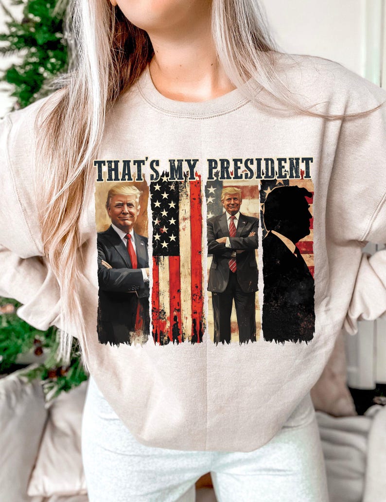 May include: A beige sweatshirt with a graphic print of three men in suits, with the text "THAT'S MY PRESIDENT" above them. The graphic also includes an American flag.