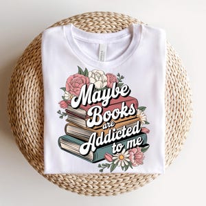May include: White t-shirt with a floral design and the text "Maybe books are addicted to me".
