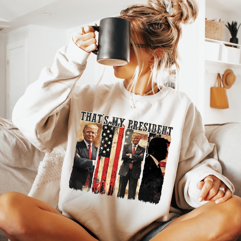 May include: A white sweatshirt with the text "That's My President" and images of three men in front of an American flag.