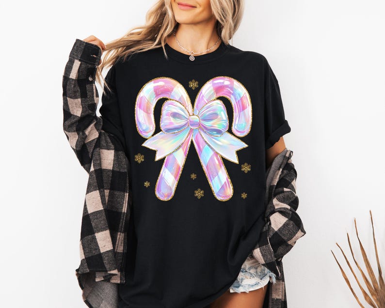 May include: Black t-shirt featuring a large, iridescent candy cane design with a bow and gold accents. The candy canes have a plaid pattern in pastel colors. Gold snowflake accents are scattered around the design.