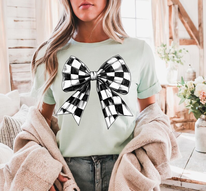 May include: A light green t-shirt featuring a black and white checked bow design.