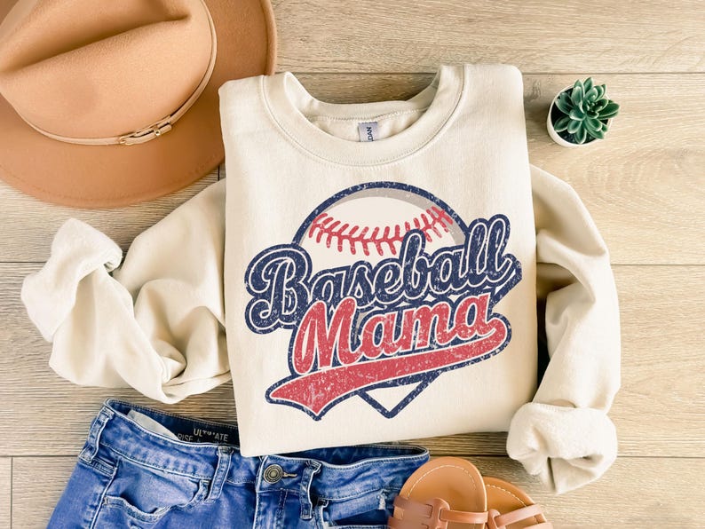 May include: A cream-colored sweatshirt with a vintage-style baseball graphic and the text "Baseball Mama".