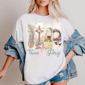 Puede incluir: Camiseta blanca con un dise&ntilde;o gr&aacute;fico de una cruz, una corona de espinas, una tumba y una rama de palma. El gr&aacute;fico est&aacute; rodeado por un efecto acuarela y el texto "true story" est&aacute; impreso debajo del gr&aacute;fico.