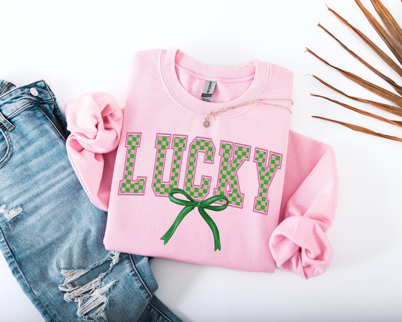 May include: Pink sweatshirt with the word "LUCKY" in green and pink checkered letters with a green bow.