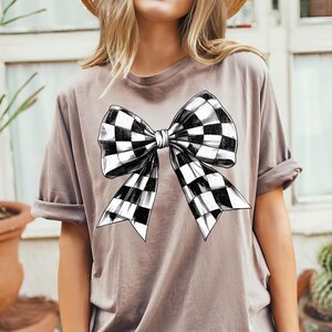 May include: A grey t-shirt with a black and white chequered bow graphic.