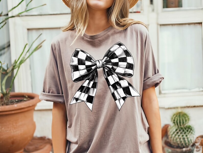 May include: A grey t-shirt with a black and white chequered bow graphic.