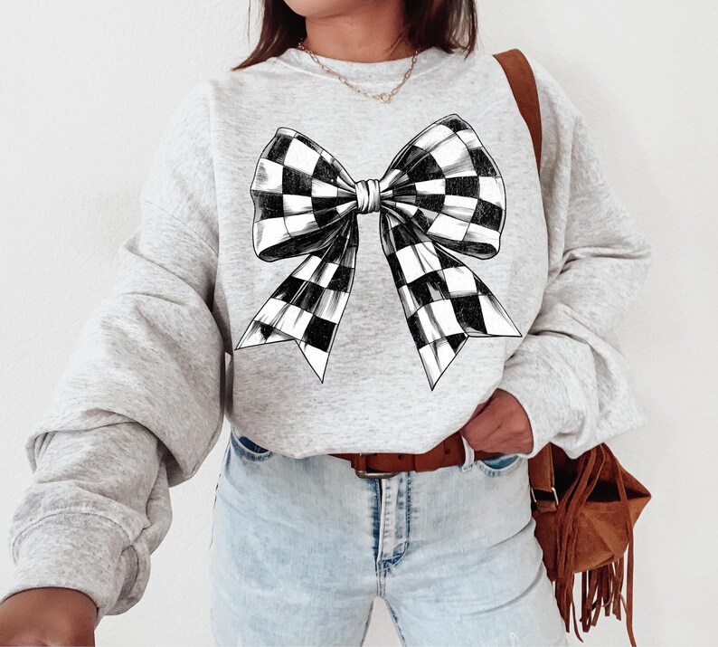 May include: A grey sweatshirt featuring a black and white checked bow design.