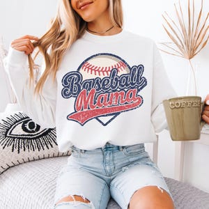 May include: White sweatshirt with a vintage baseball graphic and the text "Baseball Mama".