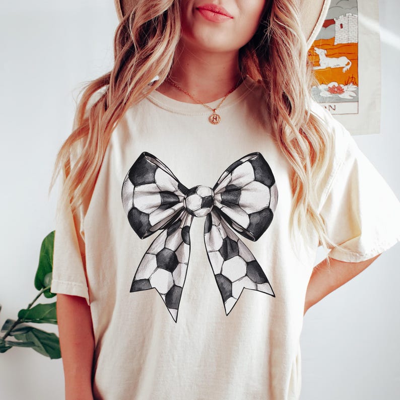 Pu&ograve; includere: T-shirt color crema con un grande design a fiocco. Il fiocco &egrave; nero e bianco, con un motivo a pallone da calcio. La maglietta ha maniche corte e una vestibilit&agrave; rilassata, adatta per l'uso quotidiano.