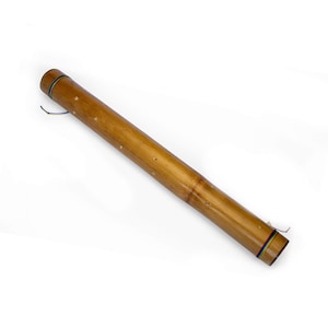 May include: A brown bamboo rain stick with a colorful string tied around the end. The rain stick has small holes drilled into the side.
