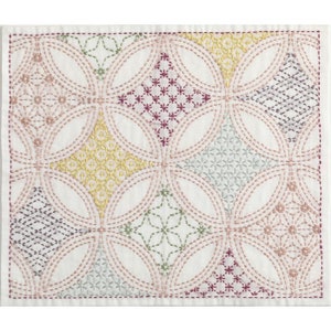 May include: A white fabric square with a repeating pattern of embroidered circles and diamonds in shades of pink, green, yellow, and gray.