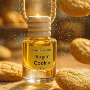 May include: A small glass bottle of "Sugar Cookie" fragrance oil with a wooden top and a braided rope. The bottle is surrounded by cookies and has a label that reads "Royal Lotus Scents". The bottle contains 8 ml of oil.