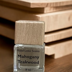 May include: A clear glass bottle with a wooden cap and a label that reads "Royal Lotus Scents Mahogany Teakwood 8 ml".