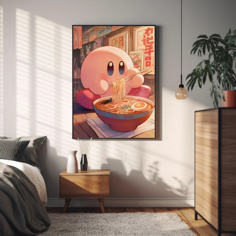 May include: A framed art print featuring a pink cartoon character eating ramen noodles from a red bowl with chopsticks. The character is sitting on a wooden floor in front of a window with Japanese text. The artwork has a warm, inviting color palette.