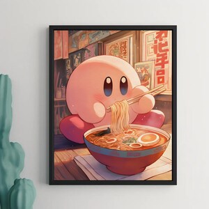 May include: A framed art print featuring a pink cartoon character eating ramen noodles with chopsticks. The character is round with large blue eyes and pink feet. The ramen bowl is red with a blue rim, and the background shows a restaurant setting.