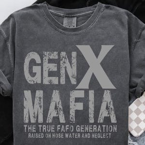 May include: Dark gray crewneck sweatshirt with the text "GEN X MAFIA" in distressed gray lettering. Below the text is "THE TRUE FAFO GENERATION RAISED ON HOSE WATER AND NEGLECT". The sweatshirt has a vintage, worn look.