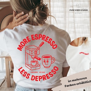 Könnte beinhalten: Weißes T-Shirt mit rotem Grafikdesign, das eine Kaffeemaschine, eine lächelnde Tasse und den Text "MORE ESPRESSO LESS DEPRESSO" zeigt. Das Shirt hat auch den Text "PURE VIBES EST.2025."