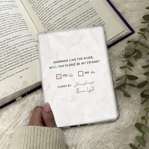 May include: A white phone case featuring the text "SHANNON LIKE THE RIVER, WILL YOU PLEASE BE MY FRIEND?" with "YES" and "NO" check boxes. The "YES" box is ticked. Signed by Johnny Kavanagh and Shannon Lynch.
