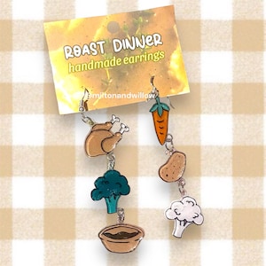 Op de afbeelding: Handgemaakte oorbellen met het thema geroosterd diner met een bruine kalkoen, groene broccoli, een bruine kom, een bruine aardappel en een oranje wortel.