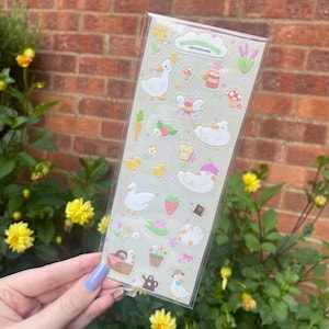 May include: A clear sticker sheet with illustrations of ducks, ducklings, and garden-themed elements. The stickers include a duck with a flower crown, a fairy, mushrooms, strawberries, and a picnic basket. The text "COTTAGECORE DUCKS" is printed at the top.