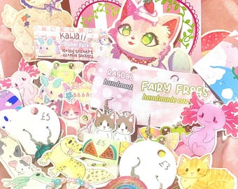 May include: A collection of handmade earrings featuring cute animal designs, including cats, axolotls, and frogs. The earrings are displayed on a pink background with other kawaii stickers and charms.